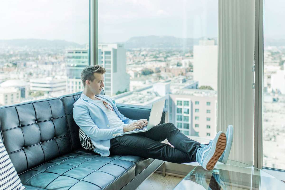 Man in high rise apartment sitting on sofa with laptop