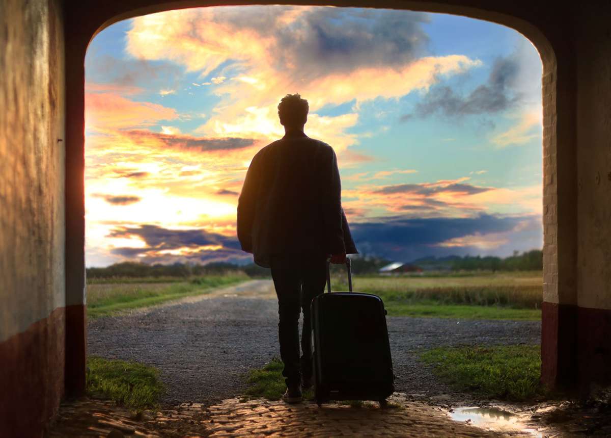 Man leaving into the sunset with suitcase