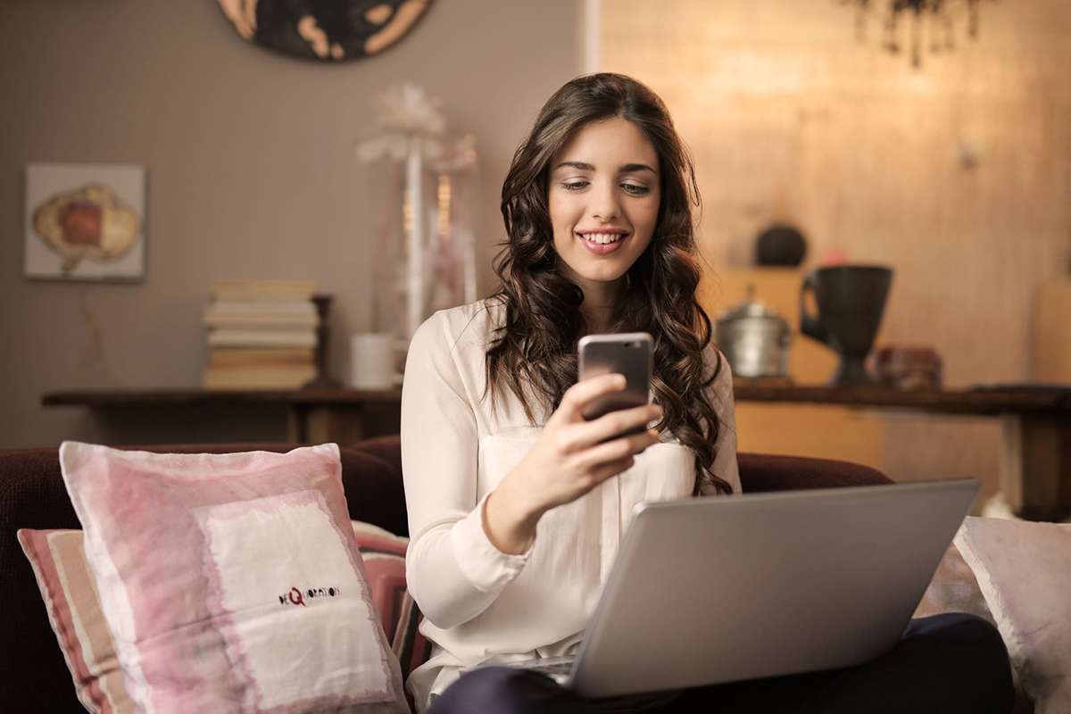 Woman with laptop looking at mobile phone